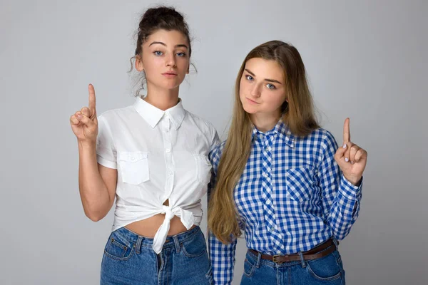 Ürün, gri arka plan üzerinde izole için yukarıyı mutlu iki genç kız kardeş