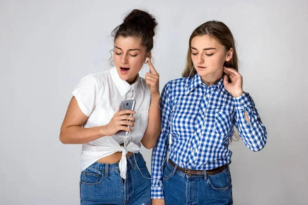 Δύο Νεαρές Αδελφές Ακουστικά Στέκεται Και Ακούτε Μουσική Μέσω Γκρι — Φωτογραφία Αρχείου
