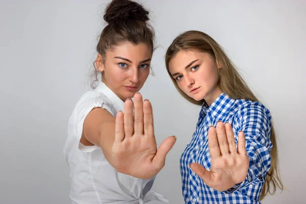 Dur bir el ile gösterilen ve kameraya bakarak gri arka plan iki genç kız üzerinde duran güzel bir kadın portresi