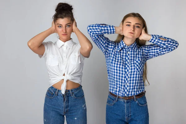 Gri arka plan üzerinde duran onların kulaklarını kapsayan iki genç kız portresi