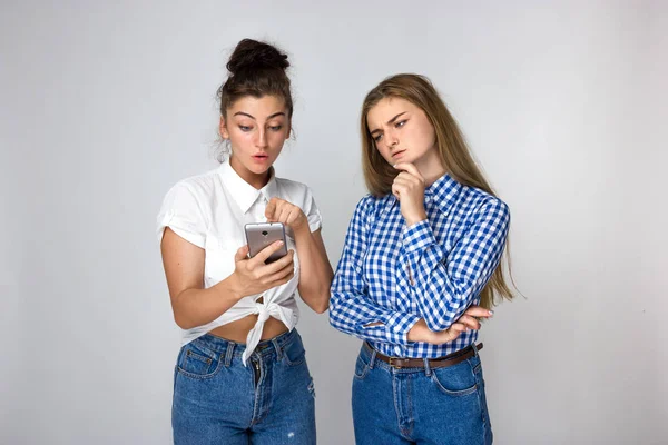 Retrato Dos Hermanas Jóvenes Que Piensan Miran Teléfono Sobre Fondo —  Fotos de Stock