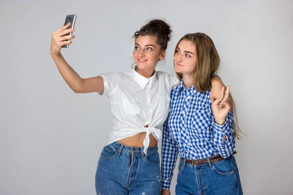 İki genç kız portresi onlar gülümsüyor ve gri arka plan üzerinde selfie ayakta yapar