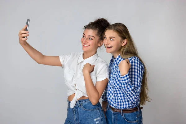 İki genç kız portresi onlar gülümsüyor ve gri arka plan üzerinde selfie ayakta yapar
