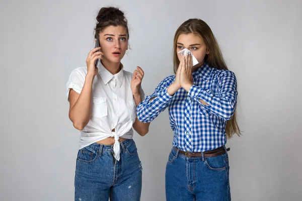 Grip olan güzel bir kadın portresi kız kardeşi bir doktor çağırır. burun ayakta gri arka plan üzerinde üfleme kız