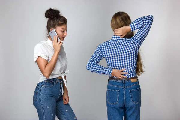 Güzel kadın kız kardeşi gri arka plan üzerinde duran bir doktor çağırır sırt ağrısı muzdarip.