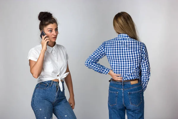 Güzel kadın kız kardeşi gri arka plan üzerinde duran bir doktor çağırır sırt ağrısı muzdarip