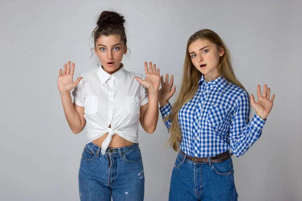 Zwei Junge Schwestern Stehen Mit Erhobenen Händen Zur Seite Und lizenzfreie Stockfotos