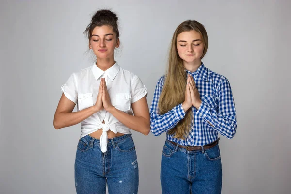 Zwei Junge Schwestern Beten Stehend Vor Grauem Hintergrund Stockbild