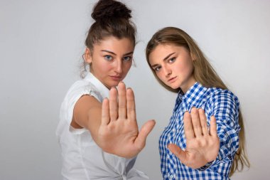 Dur bir el ile gösterilen ve kameraya bakarak gri arka plan iki genç kız üzerinde duran güzel bir kadın portresi