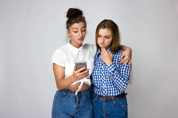 Retrato Dos Hermanas Jóvenes Que Piensan Miran Teléfono Sobre Fondo — Foto de Stock