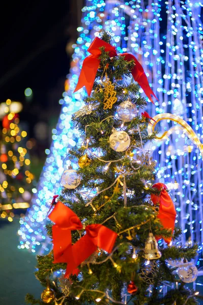 blur image of artificial pine christmas tree decorated with red bow tie , ball , gift and big blue light bulb christmas tree