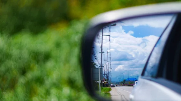 在汽车的镜面反射中 有街道 电线杆和多云的天空 有绿色散背景 — 图库照片