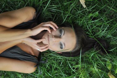 Genç kadın bir bahçe açık portre çim üzerinde yalan. Koyu saçlı kadın genç kız portresi kapatın. Üst yukarıdan havai görüntüleyin. Bahar Yaz gençlik mutluluk kavramı