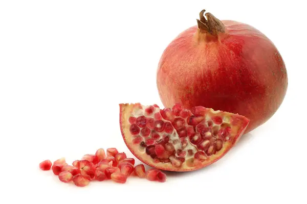 En hel granatäpple (Punica granatum), en klippa bit och frön — Stockfoto