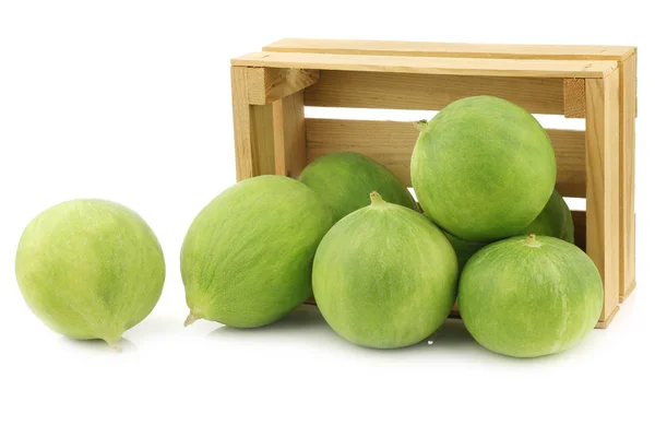 Fresh cumelo\'s (mix between a cucumber and a melon) in a wooden crate on a white background