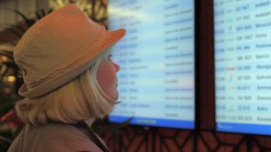 Havaalanında gidiş bilgi kurulu bir kadın bakar.