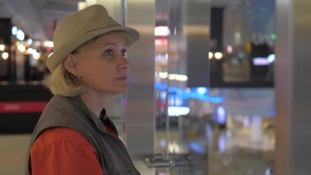 Μια ενήλικη γυναίκα βόλτες το κιγκλίδωμα και κοιτάζει γύρω από το αεροδρόμιο. — Αρχείο Βίντεο
