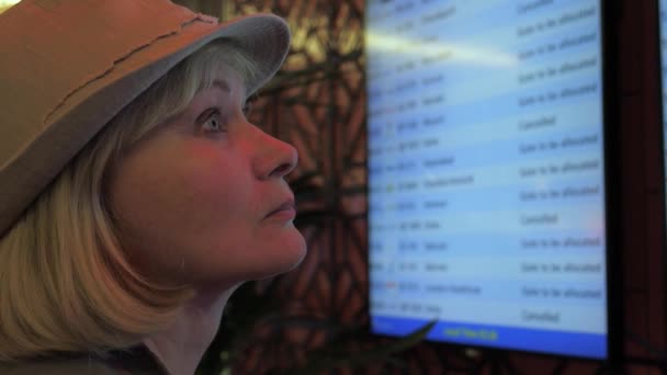 Une femme regarde le panneau d'information des départs à l'aéroport . — Video