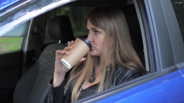 Ung vacker kvinna som sitter i bilen och dricka kaffe — Stockvideo