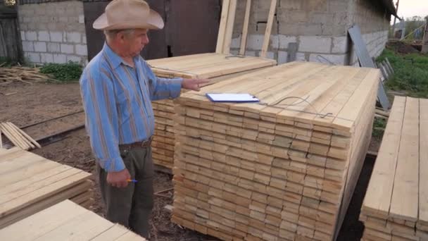 Empresario va a lo largo de los tableros de madera embalados, dice y muestra la producción — Vídeos de Stock