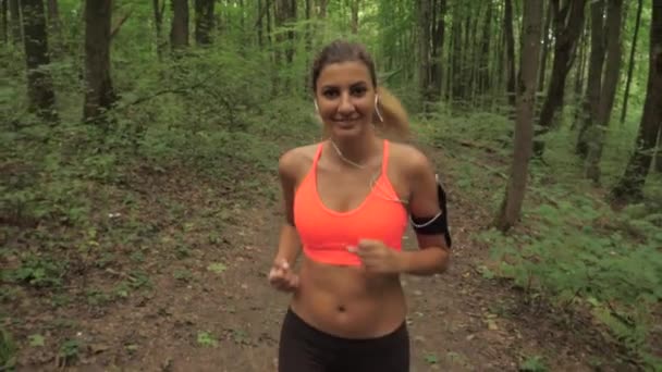 Femme brune sportive souriante aux cheveux longs courant dans le parc — Video