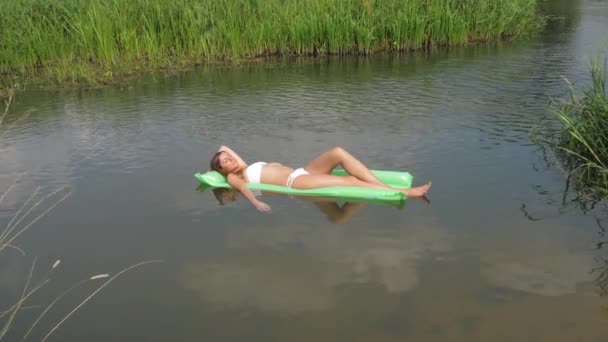 在白色泳衣日光浴铺设在水中的床垫上的年轻女子 — 图库视频影像