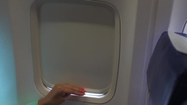 Weibliche Hand in Großaufnahme öffnet und schließt den Rollladen des Flugzeugfensters — Stockvideo