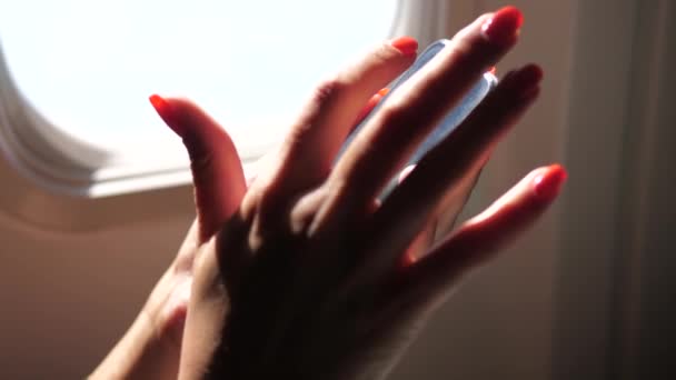 Nahaufnahme der Hand einer Frau am Telefon, die am Fenster des Flugzeugs sitzt — Stockvideo