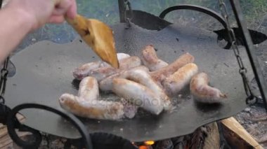 Çevrilen lezzetli sulu sosis Fry ateşte, Barbekü askıya bir tavada