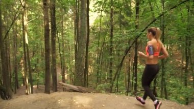 Atletik genç kadın orman iz çalışan ve tepeden aşağı gidiyor