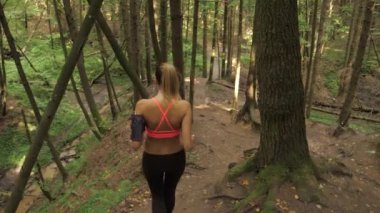 Atletik genç kadın orman iz çalışan ve tepeden aşağı gidiyor