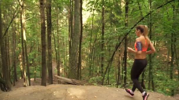 Jeune femme athlétique descendant le sentier forestier et descendant de la colline 