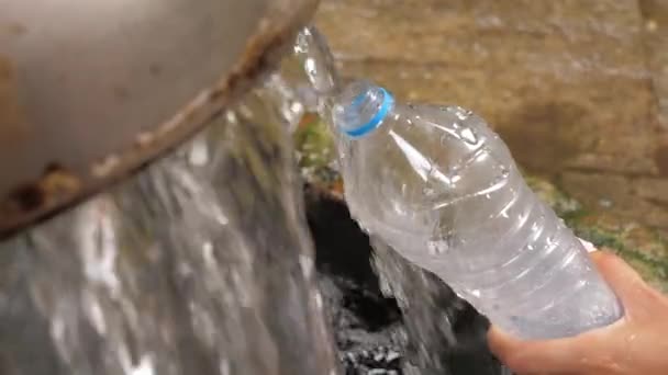 Primo piano, la mano tiene bottiglia di plastica e versa acqua pura nella fonte — Video Stock