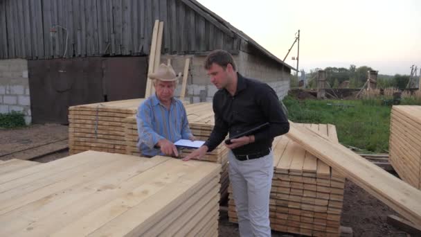 Acheteur et le vendeur à la scierie, prendre une planches en bois pour examiner — Video