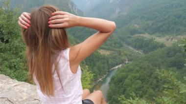 Mutlu kadın oturur ve bir nehir ile dağ Kanyon görünümünü sahiptir