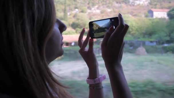 Путешествующая женщина едет на автобусе, фотографирует живописный пейзаж на смартфоне — стоковое видео
