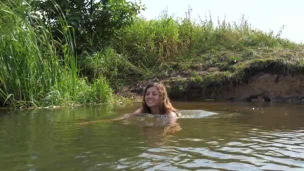 Aktive junge Frau im weißen Bikini beginnt im Fluss zu schwimmen — Stockvideo