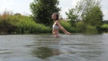 Su sıçramasına eller bel-derin su, beyaz bikinili genç oynak kadın