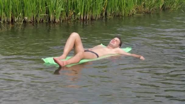 De Man rust In de warme zomer dag zwemmen In de rivier op de matras. — Stockvideo