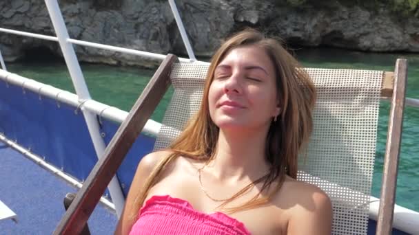 Porträt einer hübschen Frau, die sich auf einer Liege am azurblauen Meer ausruht — Stockvideo