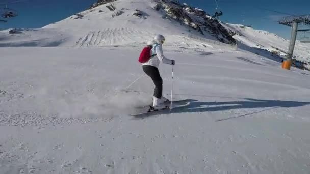 Μια γυναίκα σκι ένα σκι πίστα, ηλιόλουστη και χιονισμένο βουνά. — Αρχείο Βίντεο