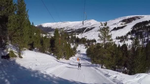 Skidåkare stiger på skidliften, rullande i snön, omgiven av skogar. — Stockvideo