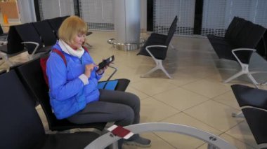 Havaalanında kalkış ve yazar bir smartphone içinde bekleyen kadın.