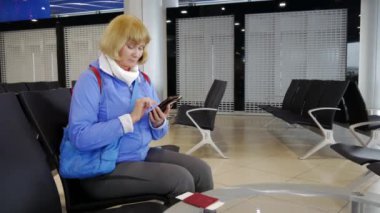 Havaalanında kalkış için bekleyen kadın ve smartphone yazdı.