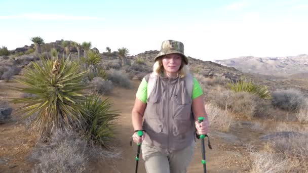 积极成熟的女子徒步旅行的足迹是在莫哈韦沙漠, 前视图 — 图库视频影像