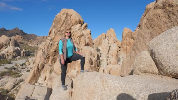 Retrato Mujer activa se para en una roca, de color arena, una pierna colocada en una piedra — Vídeos de Stock