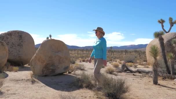 Αθλητική γυναίκα σε ένα καπέλο που πηγαίνει σε ένα έρημο Mojave, άλματα μέσα στους θάμνους — Αρχείο Βίντεο
