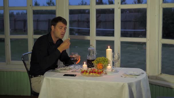 Muž sedí u stolu, pít červené víno, jíst Canape, volání číšníka — Stock video