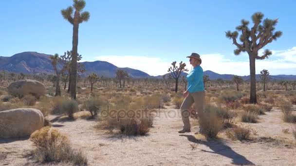 Γυναίκα ομορφιά σε ένα καπέλο που πηγαίνει σε ένα έρημο Mojave, πέτρες και Joshua Tree — Αρχείο Βίντεο