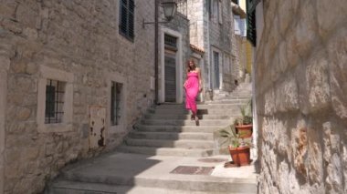 Pembe elbiseli genç güzellik kadın antik taş kenti merdivenlerden aşağı yürüyor